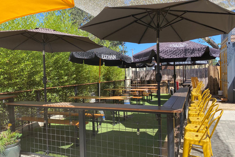 umbrellas shading a fenced grass area with beer garden tables