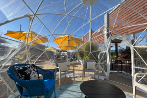plastic wintergarden igloo with a patio garden inside and yellow shade umbrellas outside in a beer garden